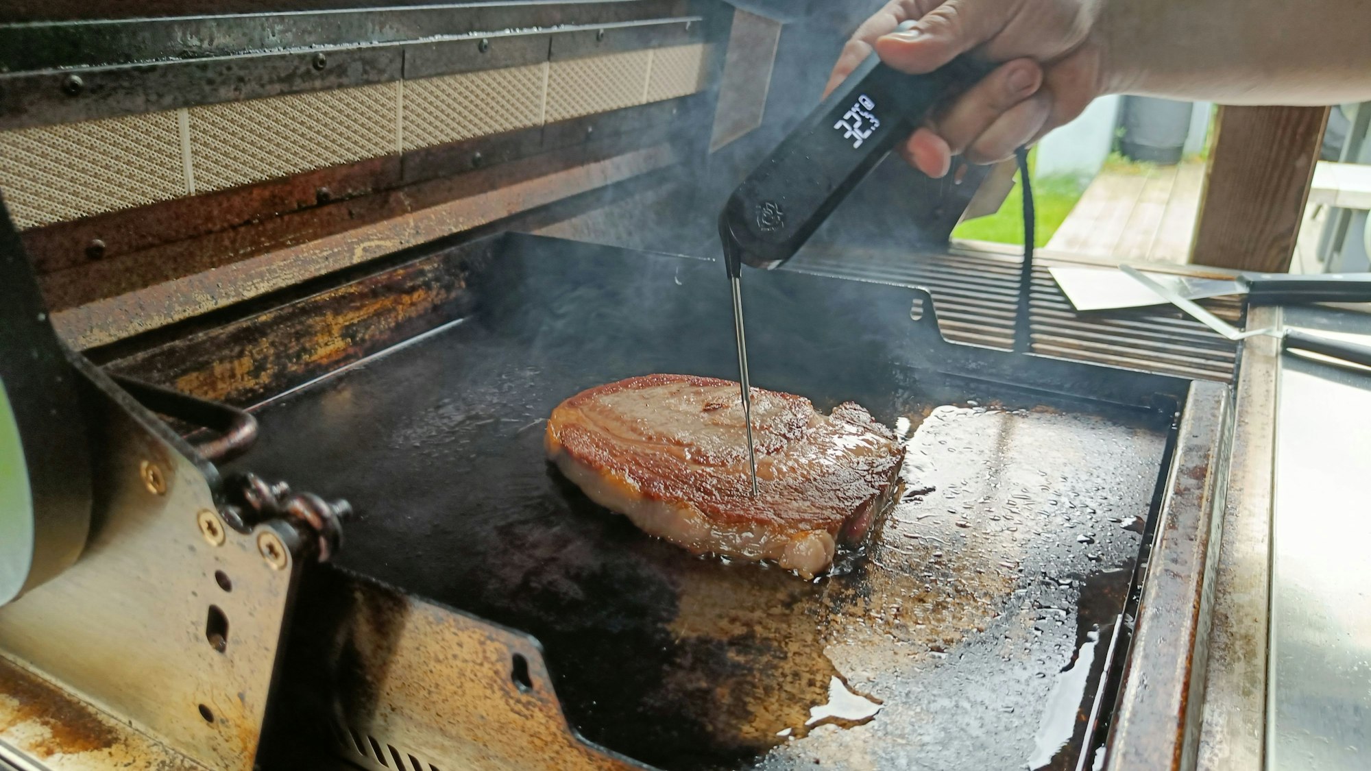 Ein Steak liegt auf dem Grill. Darin steckt ein Thermometer.