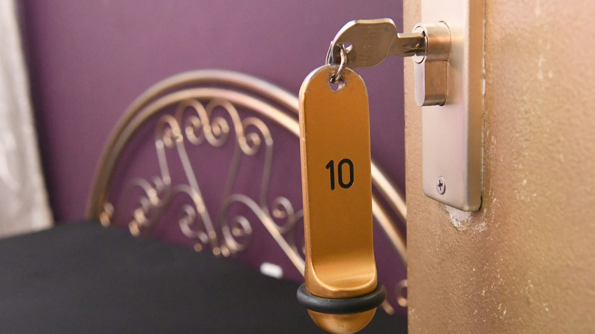 Ein Zimmerschlüssel hängt in einem Schloss an einer Zimmertür.