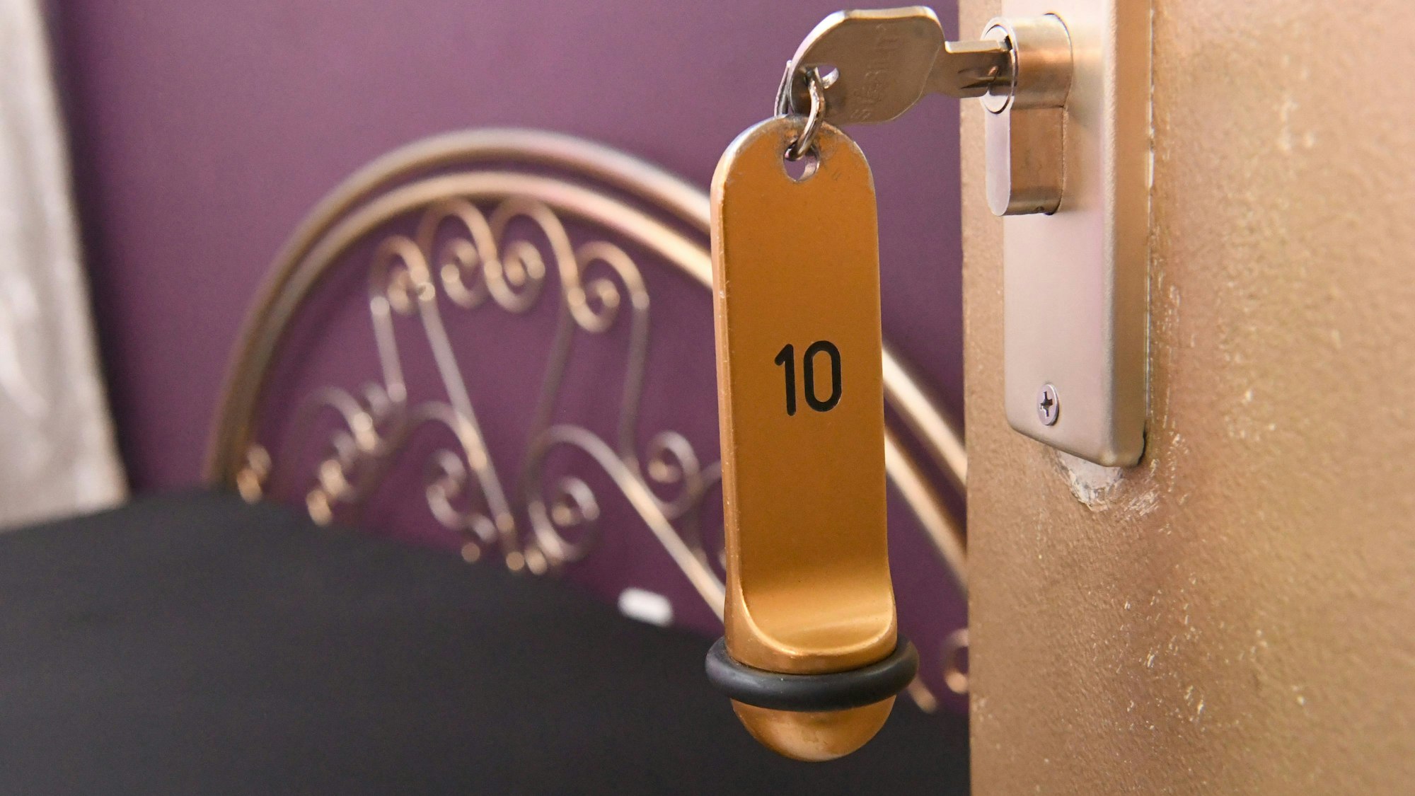 Ein Zimmerschlüssel hängt in einem Schloss an einer Zimmertür.