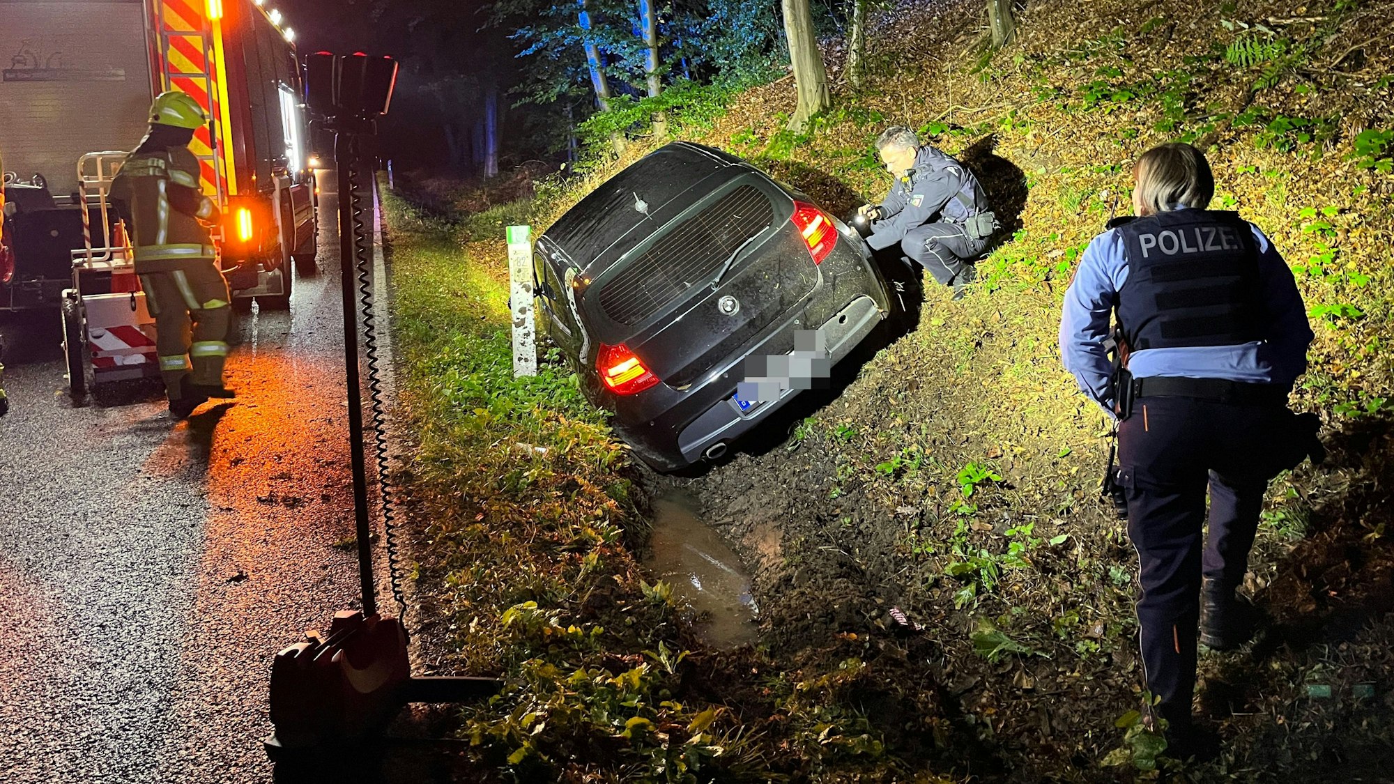 Eine 29 Jahre alte Frau aus Lohmar ust mit ihrem Auto in den Straßengraben gefahren und leicht verletzt worden. Polizisten sichern Spuren, die Feuerwehr leuchtete die Unfallstelle aus.