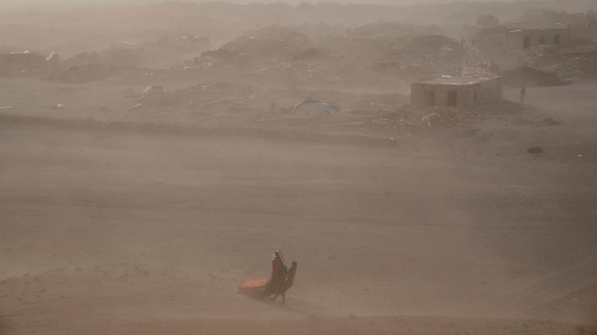 Ein afghanisches Mädchen trägt nach dem Erdbeben am 11. Oktober im Bezirk Zenda Jan gespendete Hilfsgüter zu ihrem Zelt (Archivbild). Am Sonntagmorgen erwischte ein weiteres Erdbeben die Region.