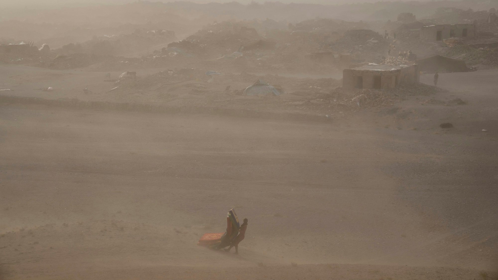 Ein afghanisches Mädchen trägt nach dem Erdbeben am 11. Oktober im Bezirk Zenda Jan gespendete Hilfsgüter zu ihrem Zelt (Archivbild). Am Sonntagmorgen erwischte ein weiteres Erdbeben die Region.