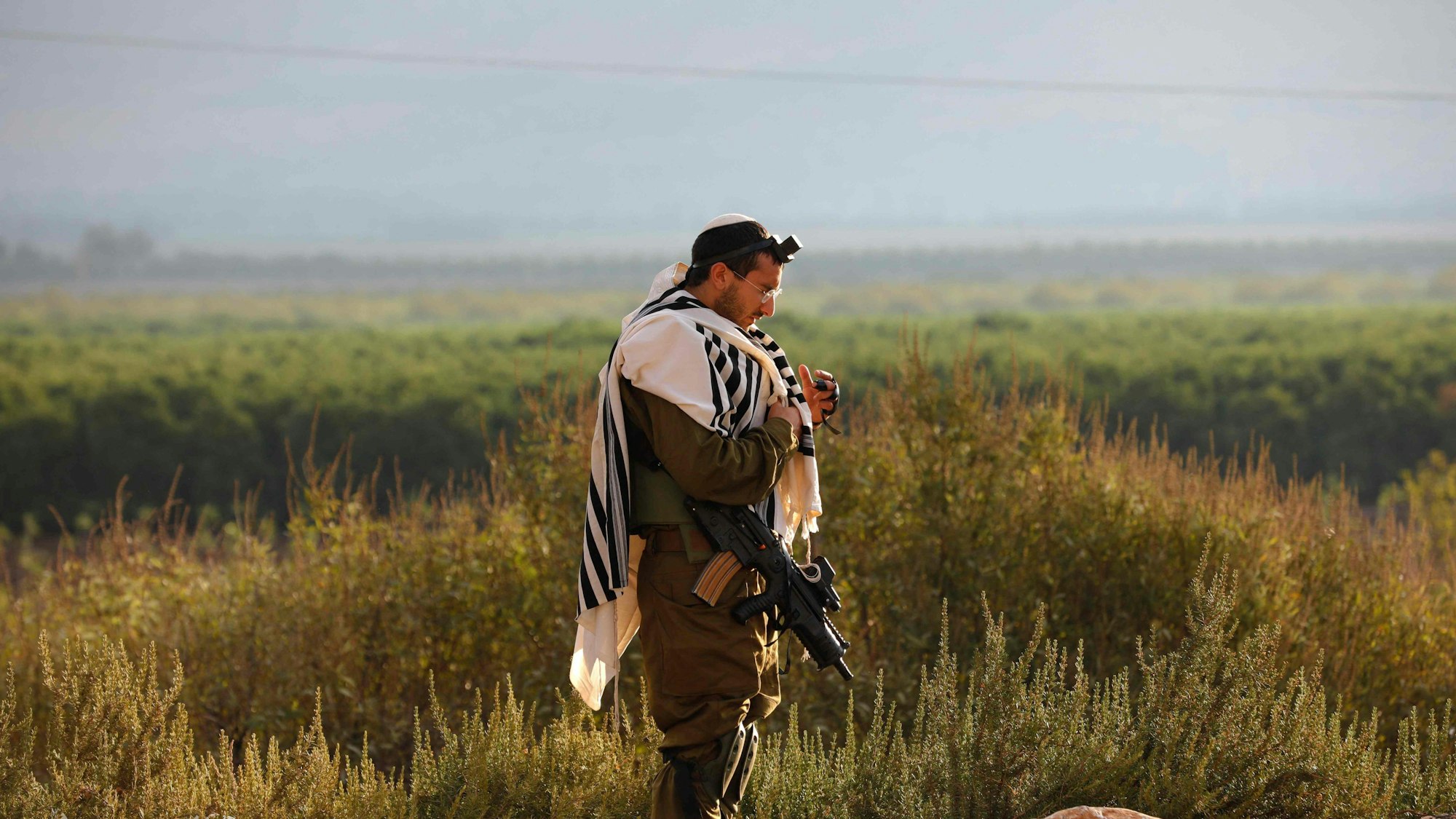 Ein israelischer Soldat, der Tefillin (Phylakterien) trägt, eine kleine schwarze Lederschatulle, die Pergamentrollen mit Versen aus der Tora enthält, betet am 15. Oktober 2023 in einer Militärposition im Norden Israels nahe der Grenze zum Libanon.