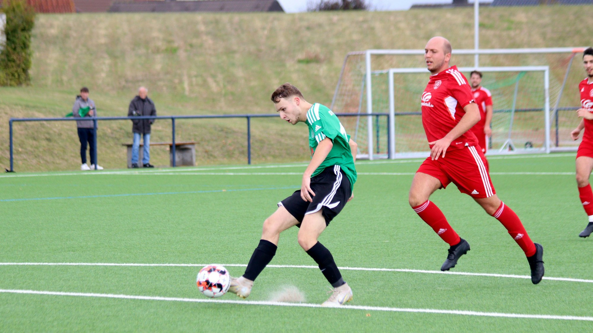 Ein Schöneseiffener Fußballspieler schießt den Ball, der Kalk der Strafraumlinie springt hoch. Der Zülpicher Verteidiger kommt zu spät.