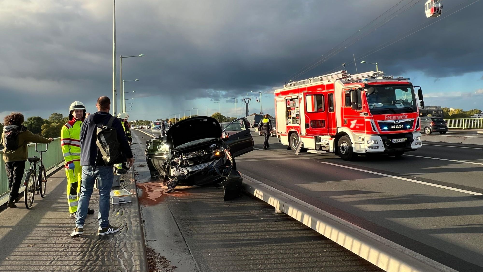 Ein verunfalltes Auto ist auf dem Radstreifen auf der Kölner Zoobrücke gelandet. Im Hintergrund steht ein Feuerwehrauto auf der Fahrbahn.