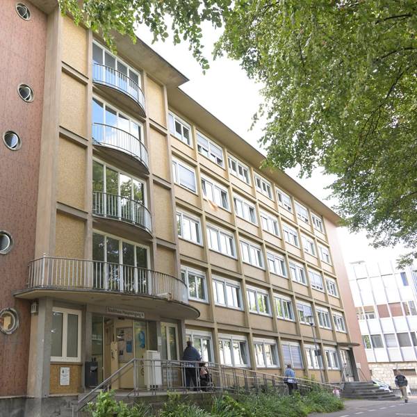 Ein vierstöckiges Verwaltungsgebäude aus den 1950er Jahren, mit langen Fensterbändern und geschwungenen Balkonen.