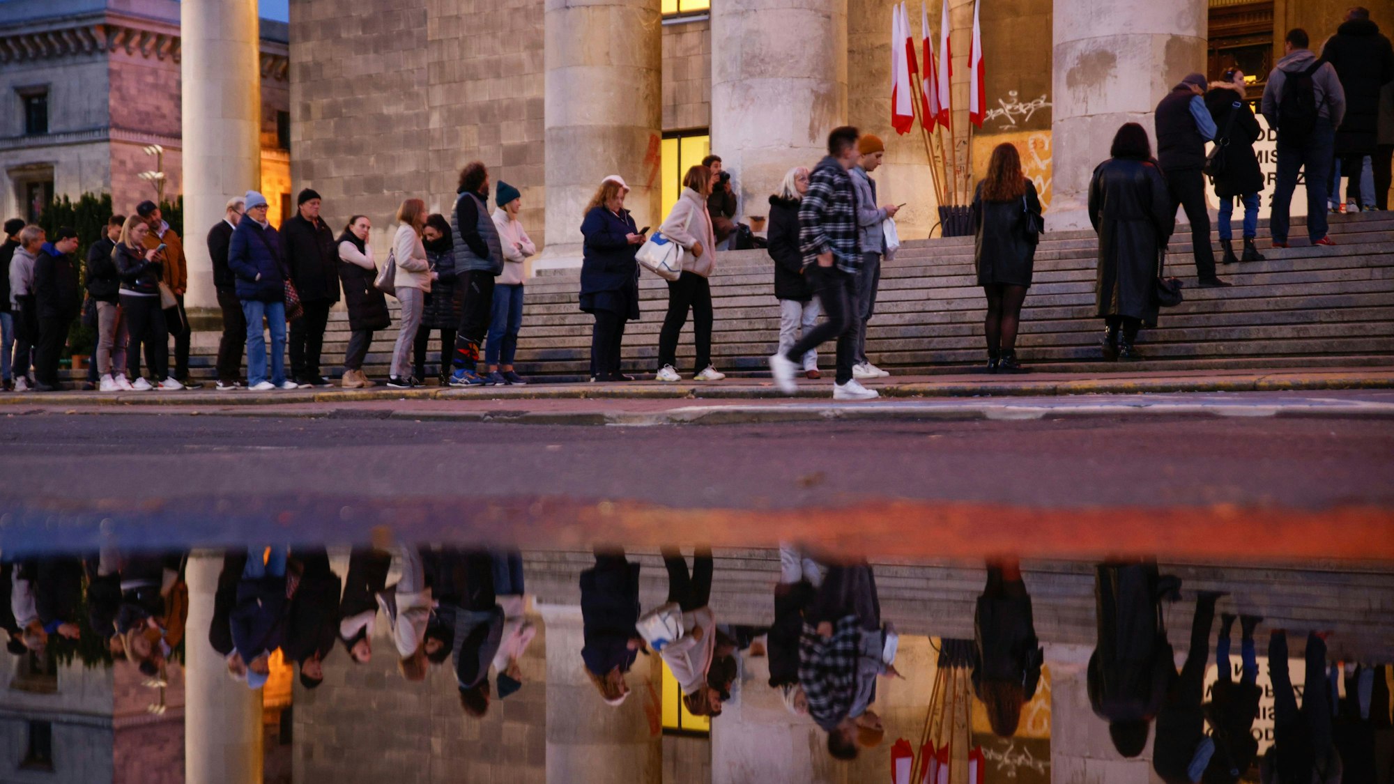 15.10.2023, Polen, Warschau: Menschen warten in einer Schlange, um ihre Stimme während der Parlamentswahlen abzugeben. Bei der Parlamentswahl in Polen hat sich eine starke Beteiligung abgezeichnet. Foto: Michal Dyjuk/AP/dpa +++ dpa-Bildfunk +++