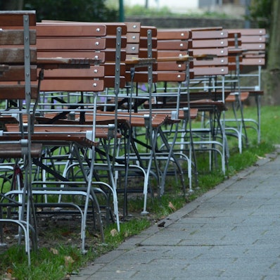 Kneipenstühle stehen an einer Straße.