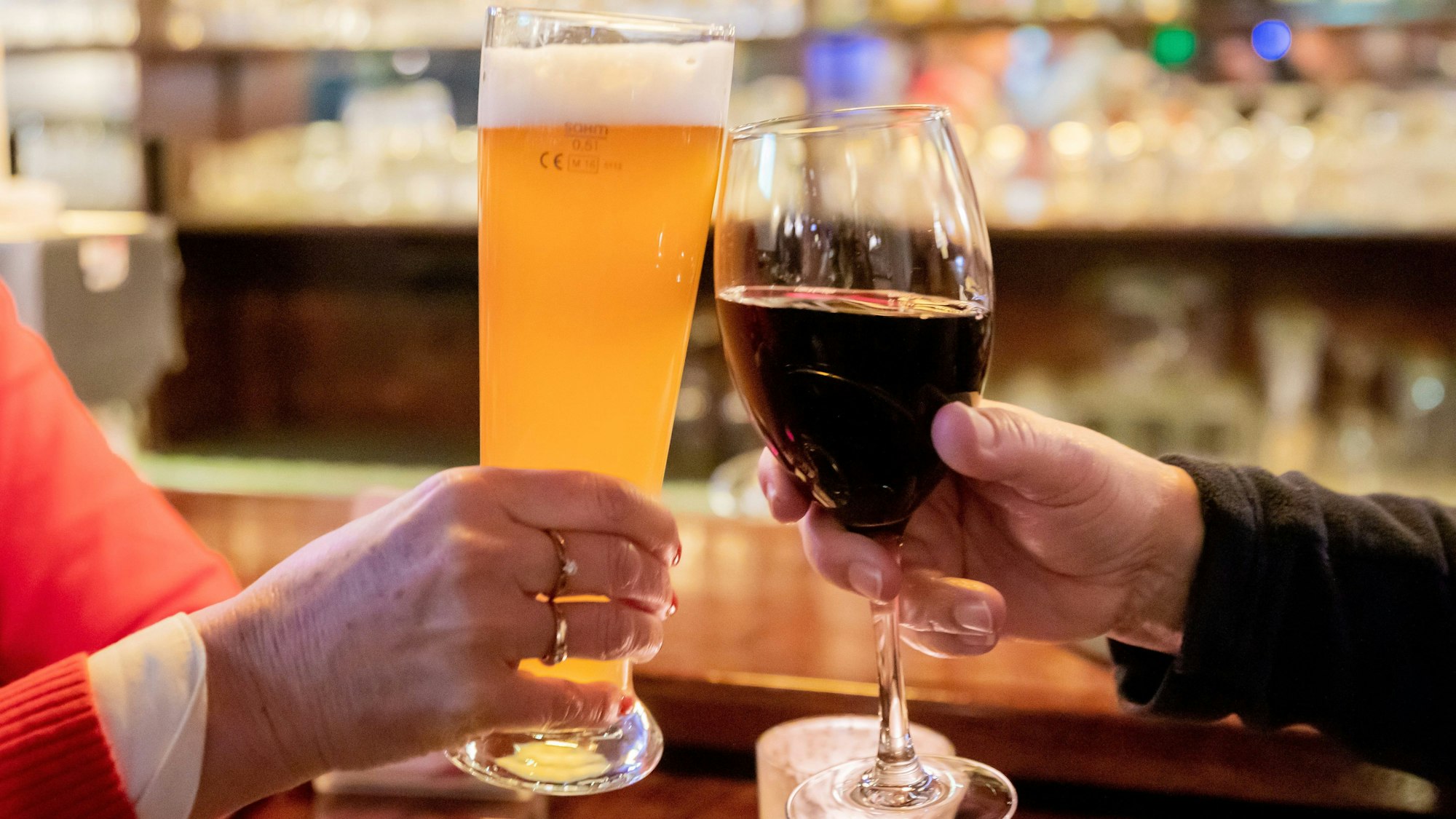 Ein Paar mit stößt mit Wein und Bier an.