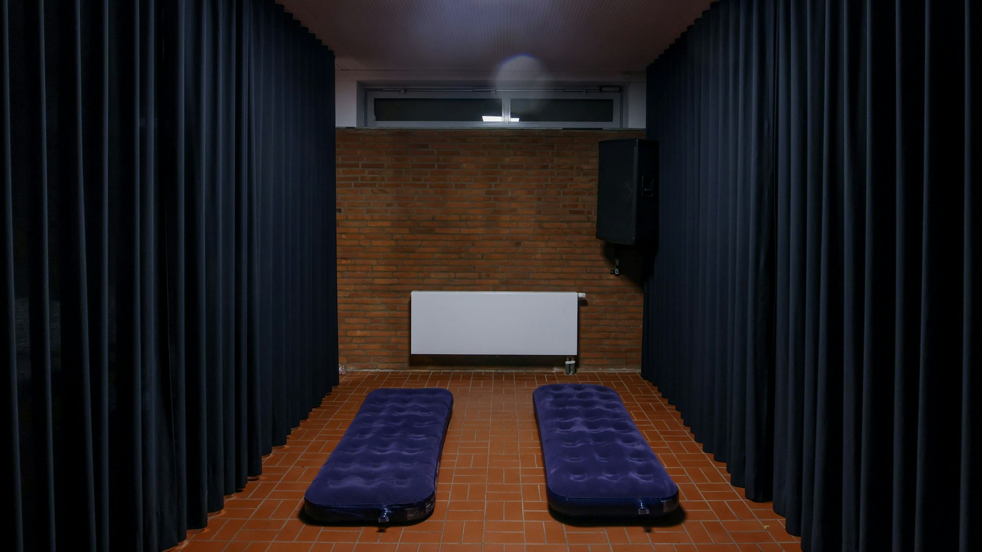 Zwei Luftmatratzen in einem karg aussehenden Raum im Souterrain.