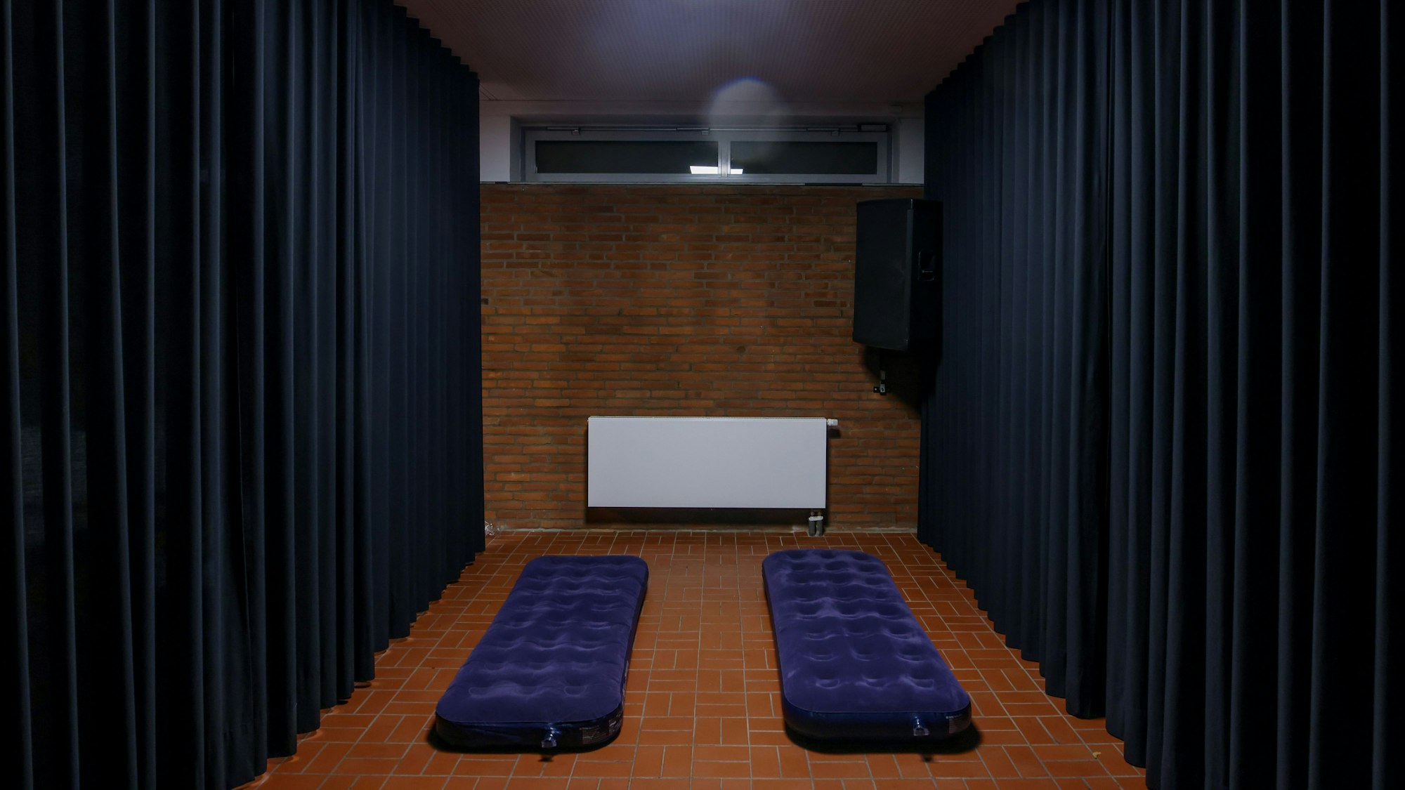 Zwei Luftmatratzen in einem karg aussehenden Raum im Souterrain.