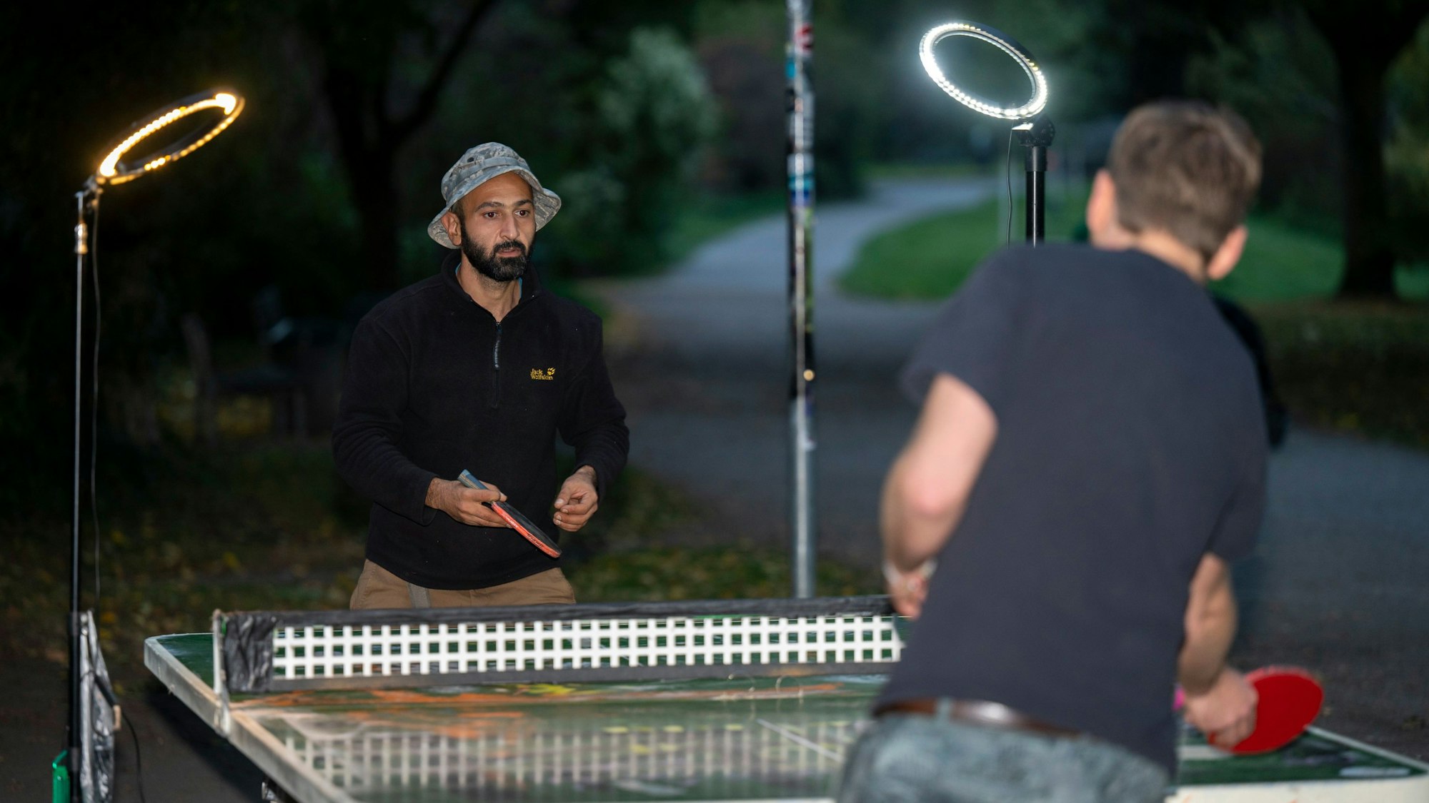 Mitinitiator der Tischtennis-Community im Lohsepark: Ali A.und Marco Stephan spielen Tischtennis auf der von Ringlichtern erleuchteten Tischtennisplatte.