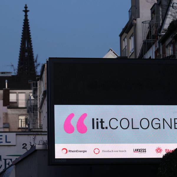 Werbung für die lit.Cologne leuchtet an einer Hausfassade in Köln.
