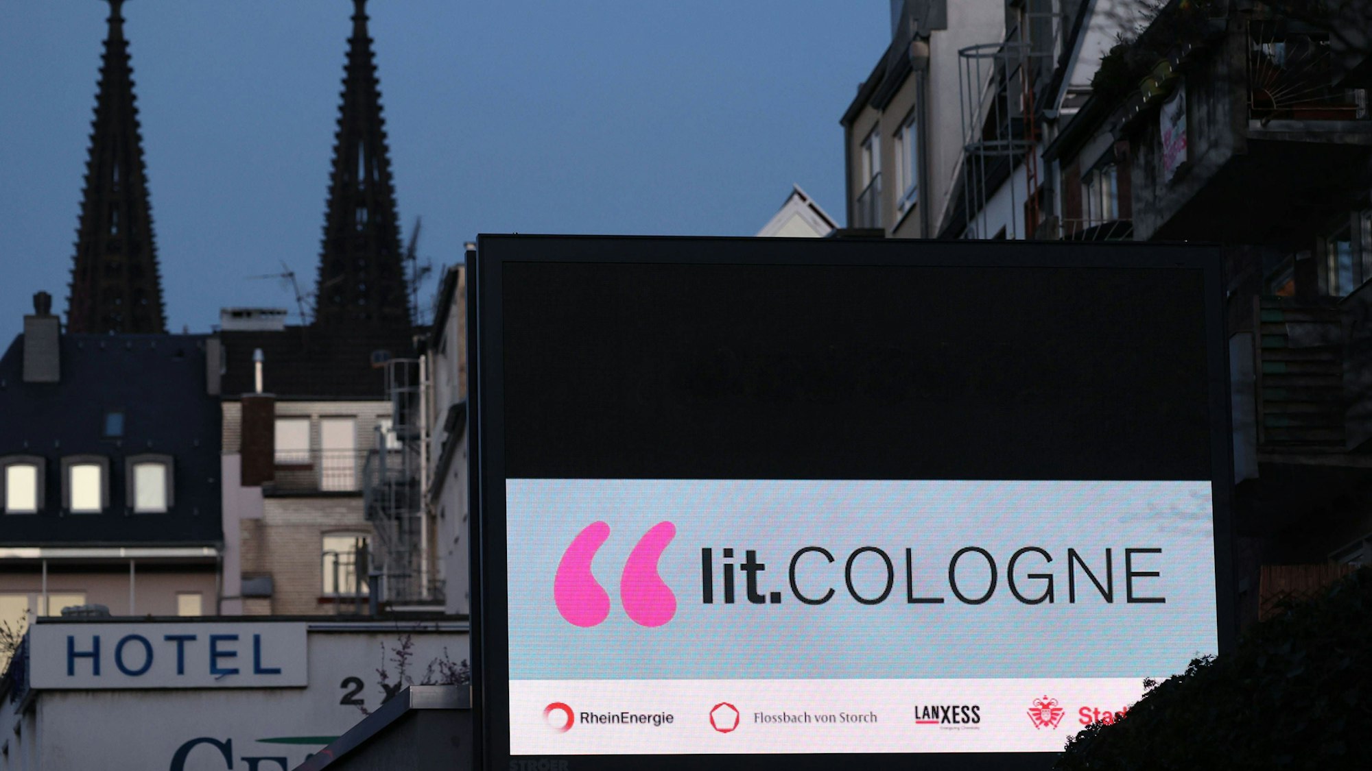Werbung für die lit.Cologne leuchtet an einer Hausfassade in Köln.