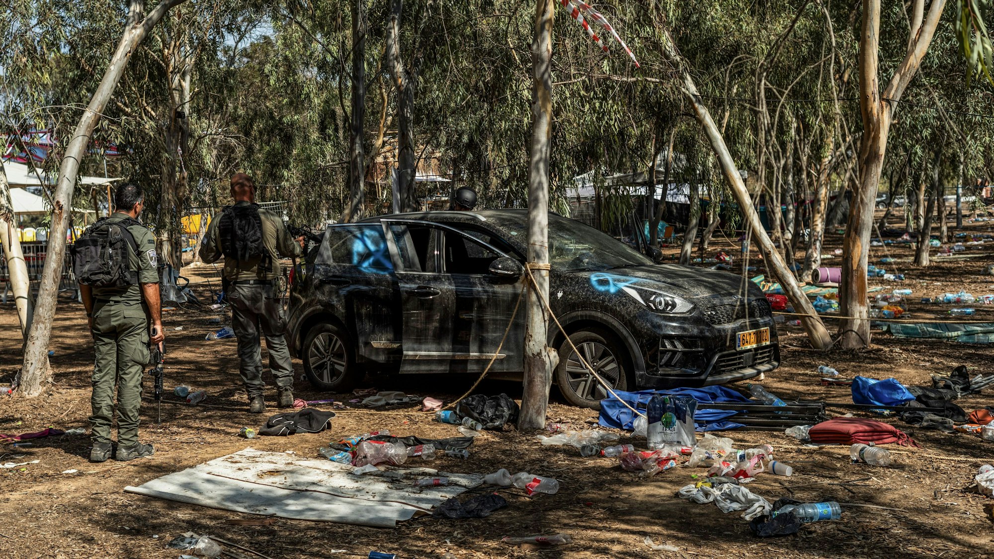 Israelische Soldaten untersuchen ein Auto auf einem Festivalgelände, bei dem die Hamas-Terroristen hunderte Menschen getötet und Geiseln genommen haben.