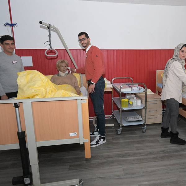 Angehende Pflegekräfte üben mit lebensgroßen Patientenpuppen in Pflegebetten ihren künftigen Berufsalltag.