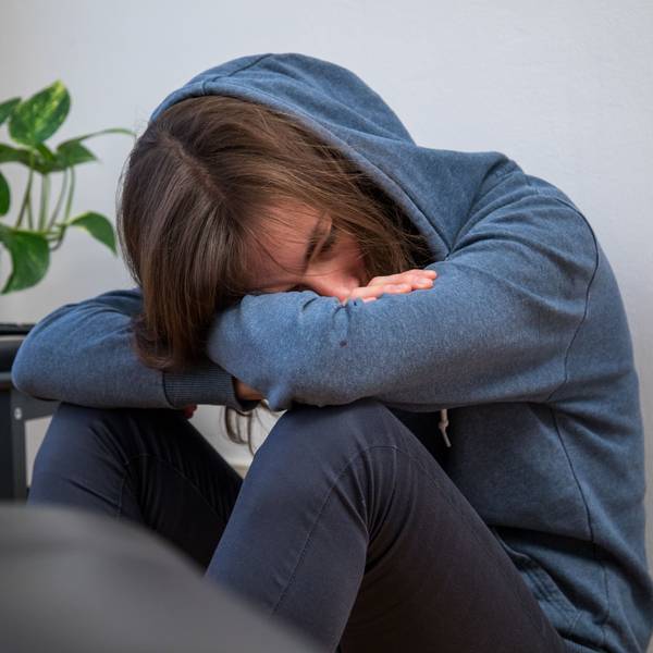 Ein Junge im blauen Kapuzenpulli lässt den Kopf hängen.