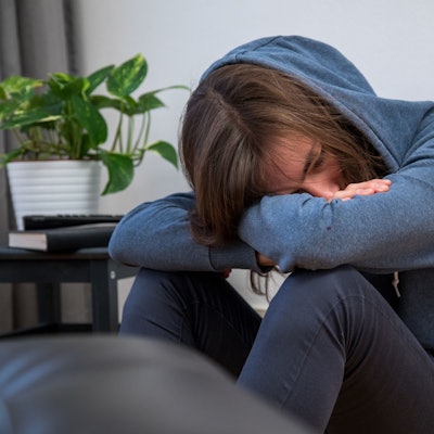 Ein Junge im blauen Kapuzenpulli lässt den Kopf hängen.