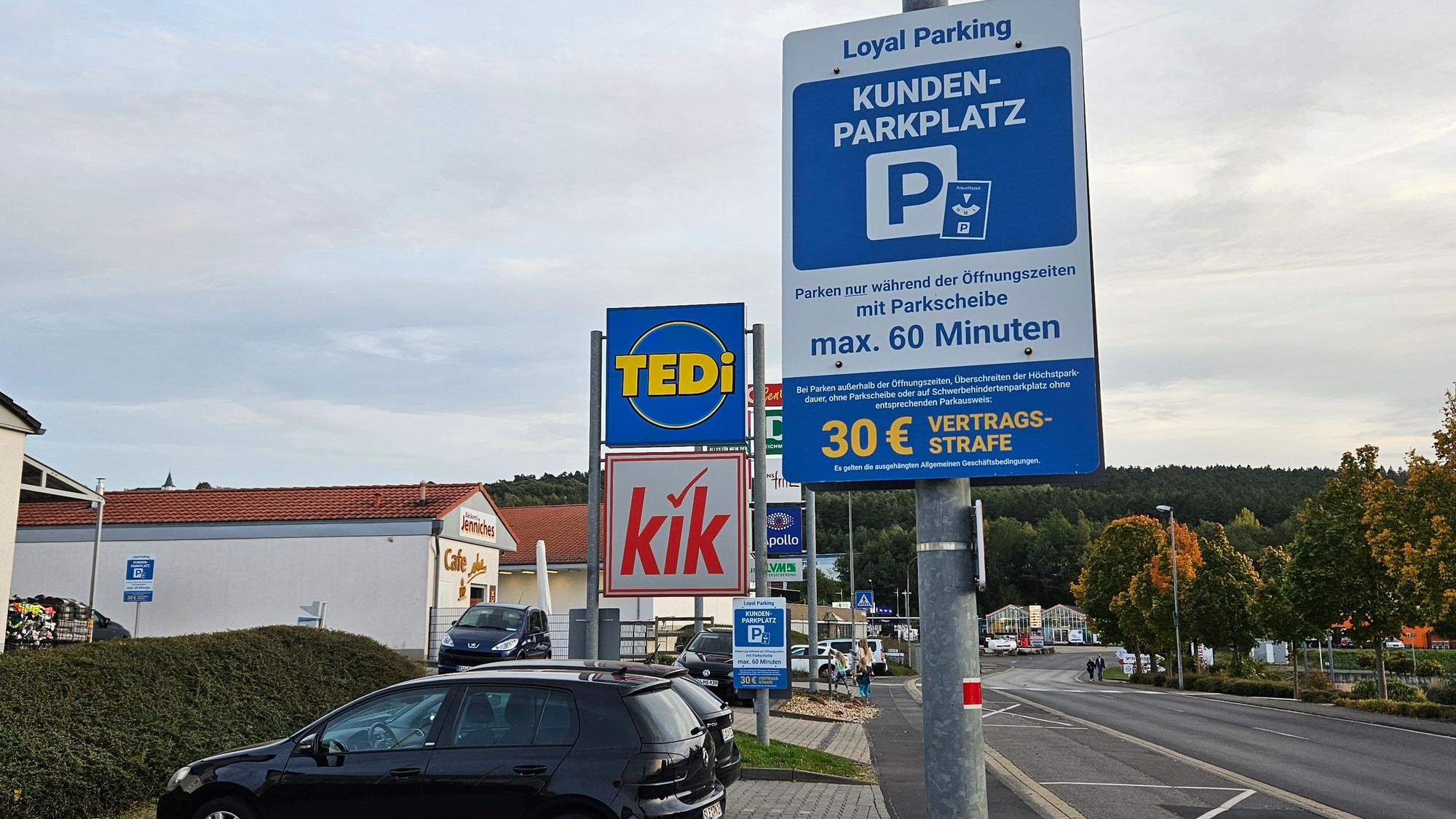 Ein Schild weist auf die maximale Parkzeit von 60 Minuten und die Vertragsstrafe von 30 Euro hin. Im Hintergrund sind die Schilder von Tedi und Kik zu sehen.