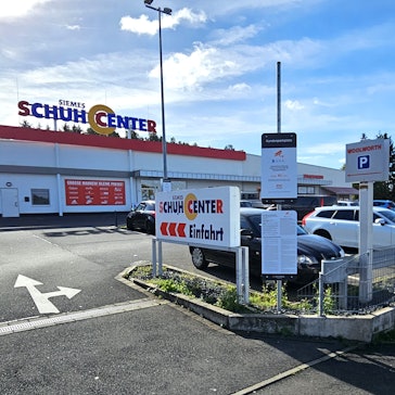 Blick auf den Parkplatz mit den Geschäften im Hintergrund.