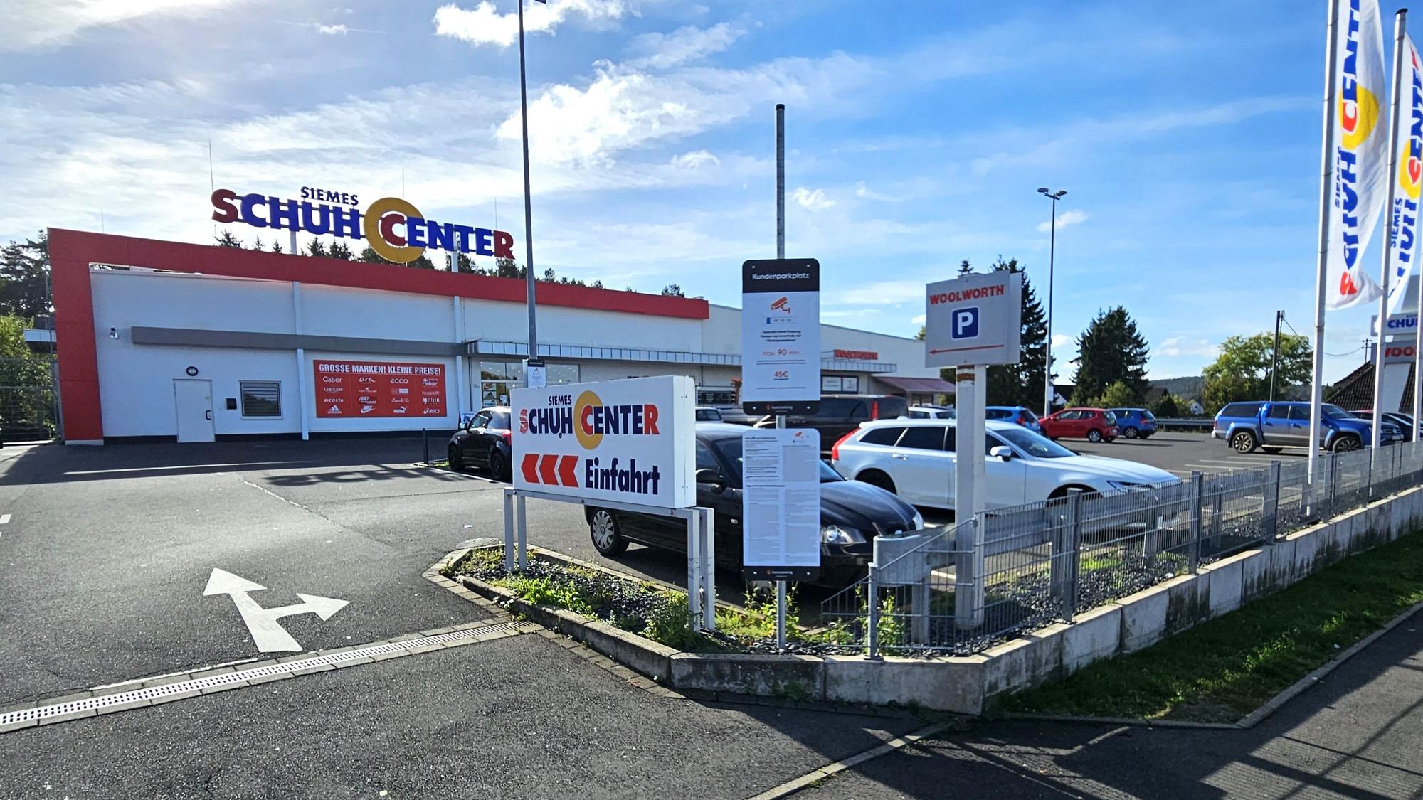 Blick auf den Parkplatz mit den Geschäften im Hintergrund.