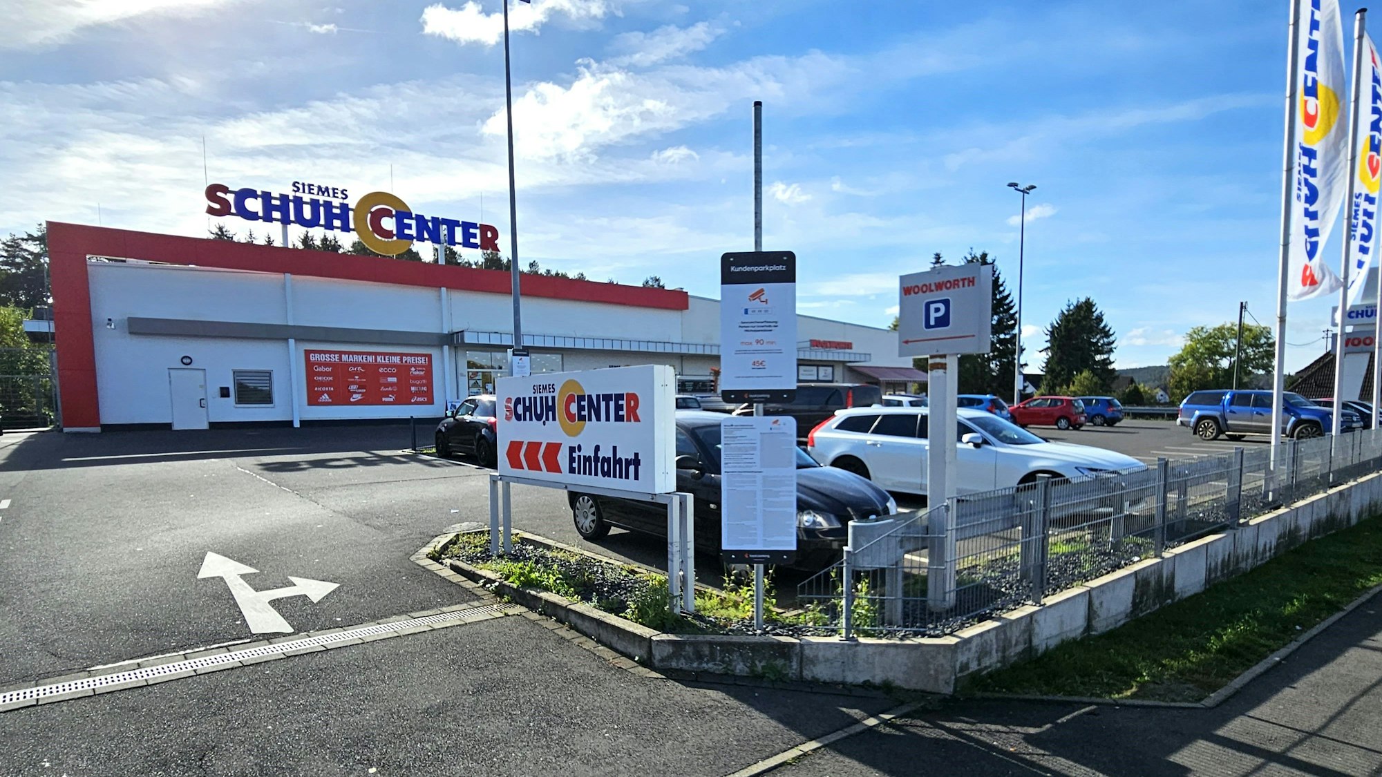 Blick auf den Parkplatz mit den Geschäften im Hintergrund.