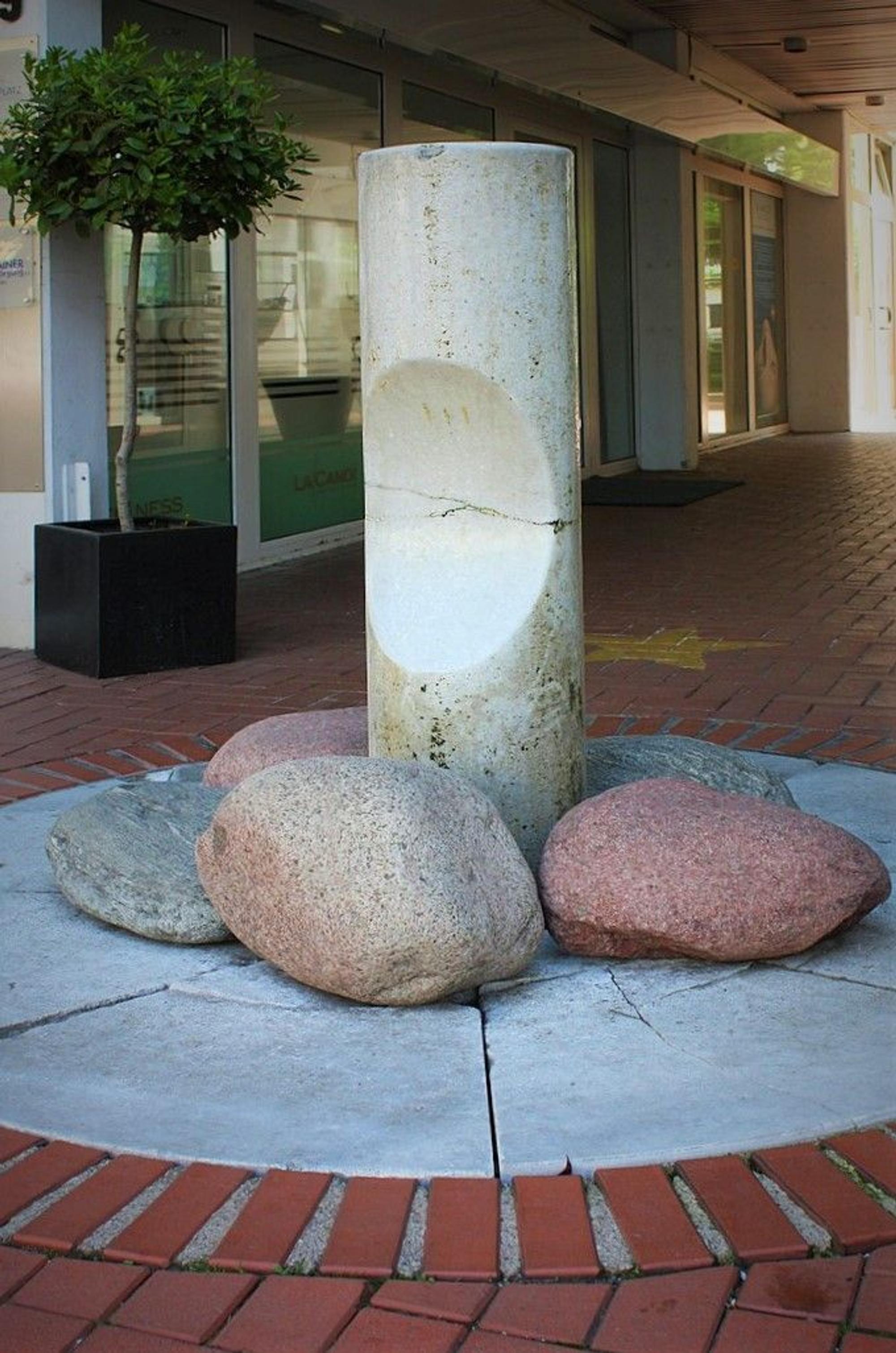 Eine Marmor-Brunnensäule mit 3 großen Kieselsteinen.