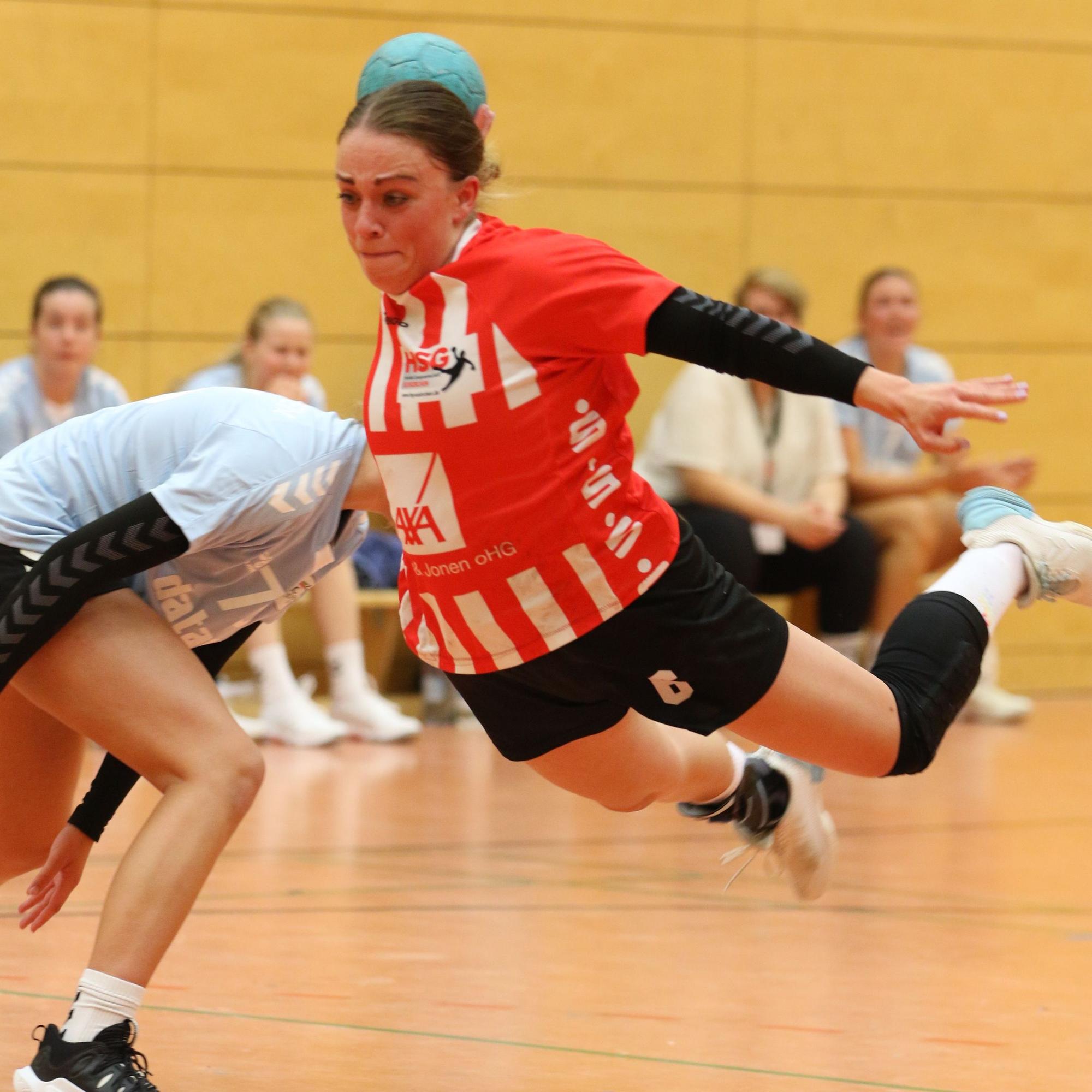 Eine Handballspielerin liegt quer in der Luft und setzt zum Wurf an.
