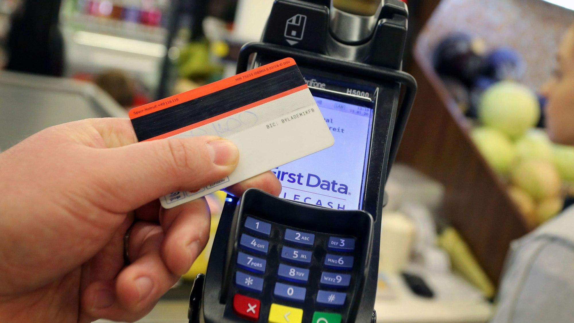 Eine EC-Karte wird an ein Kartenlesegerät gehalten.