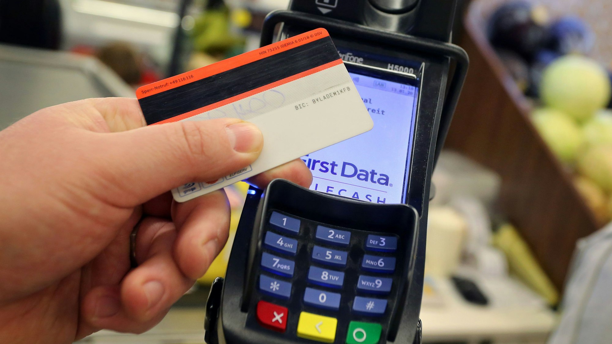 Eine EC-Karte wird an den Bezahl-Terminal an der Kasse eines Supermarktes gehalten.