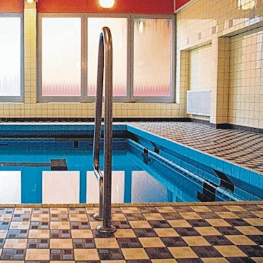 Ein Schwimmbecken mit Einstiegsleiter in einer Schwimmhalle.