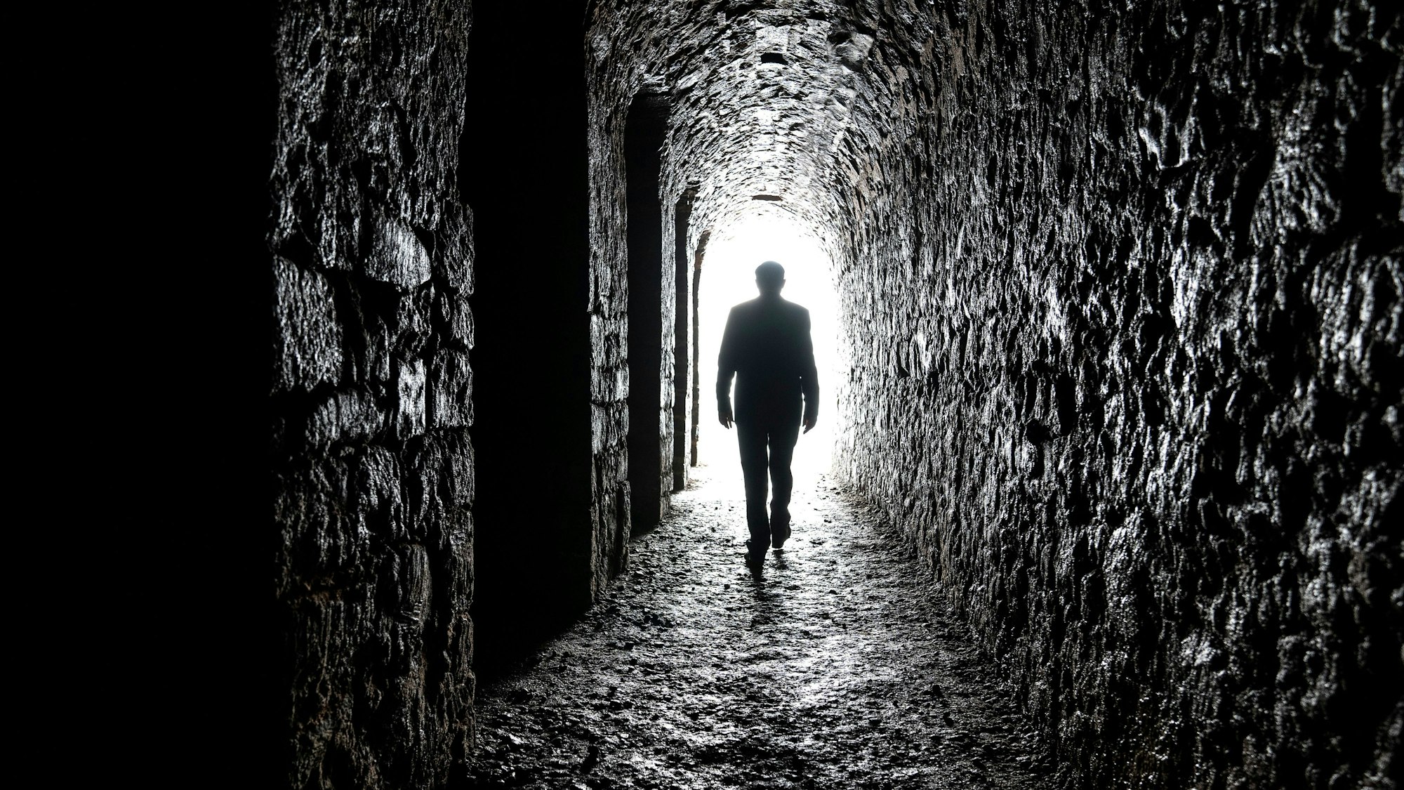 Zu sehen ist ein schwarzer Tunnel, am Ende ein Licht. Murot geht als Silhouette direkt auf das Licht zu.