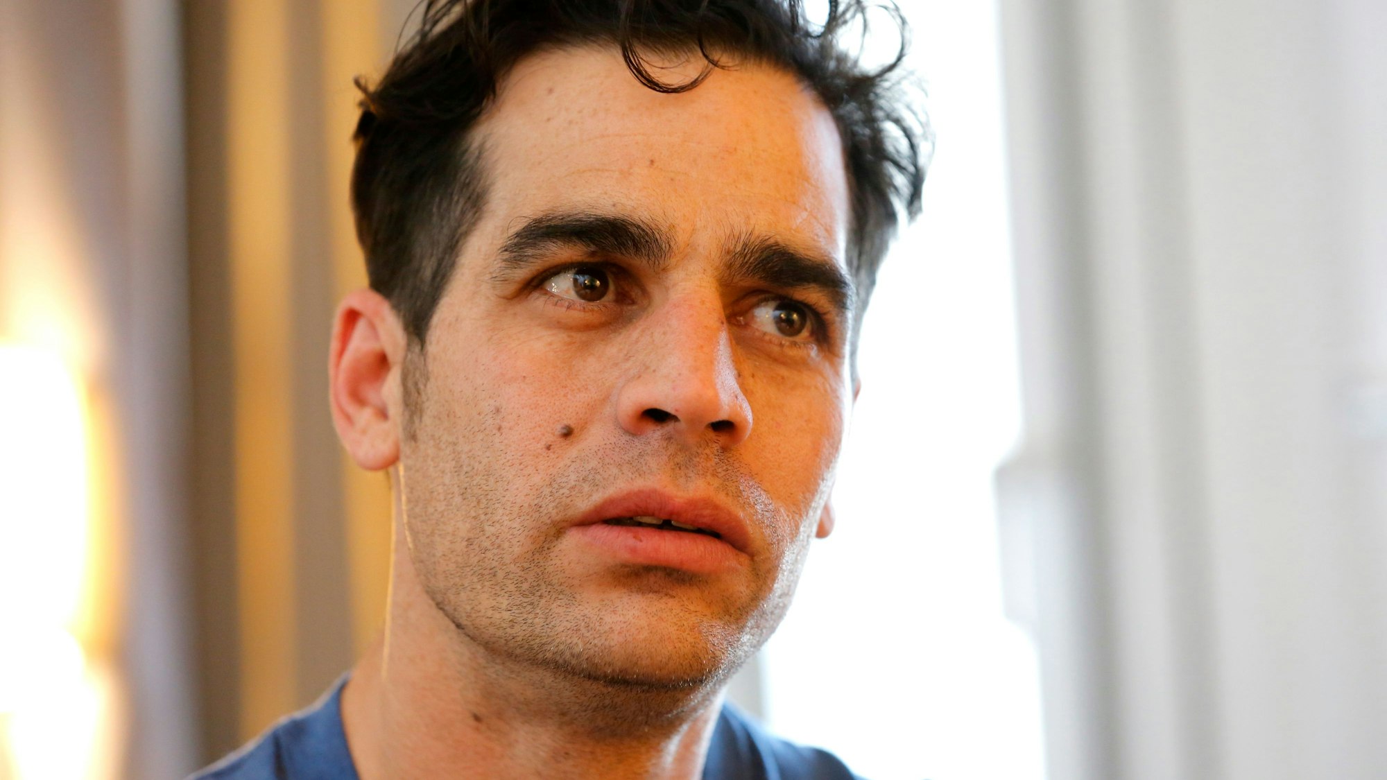 Das Foto zeigt eine Nahaufnahme von Aviv Geffen. Er schaut ernst an der Kamera vorbei. Der Hintergrund ist verschwommen.