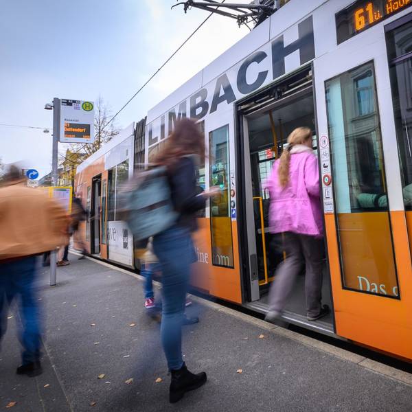 Eine Frau in einer rosa Jacke steigt an einer Bahnhaltestelle in eine Bahn der SWB ein. Weitere Personen am Bahngleis sind nicht erkennbar. Ein Mann schaut rechts im Bild aus dem Bahnfenster.