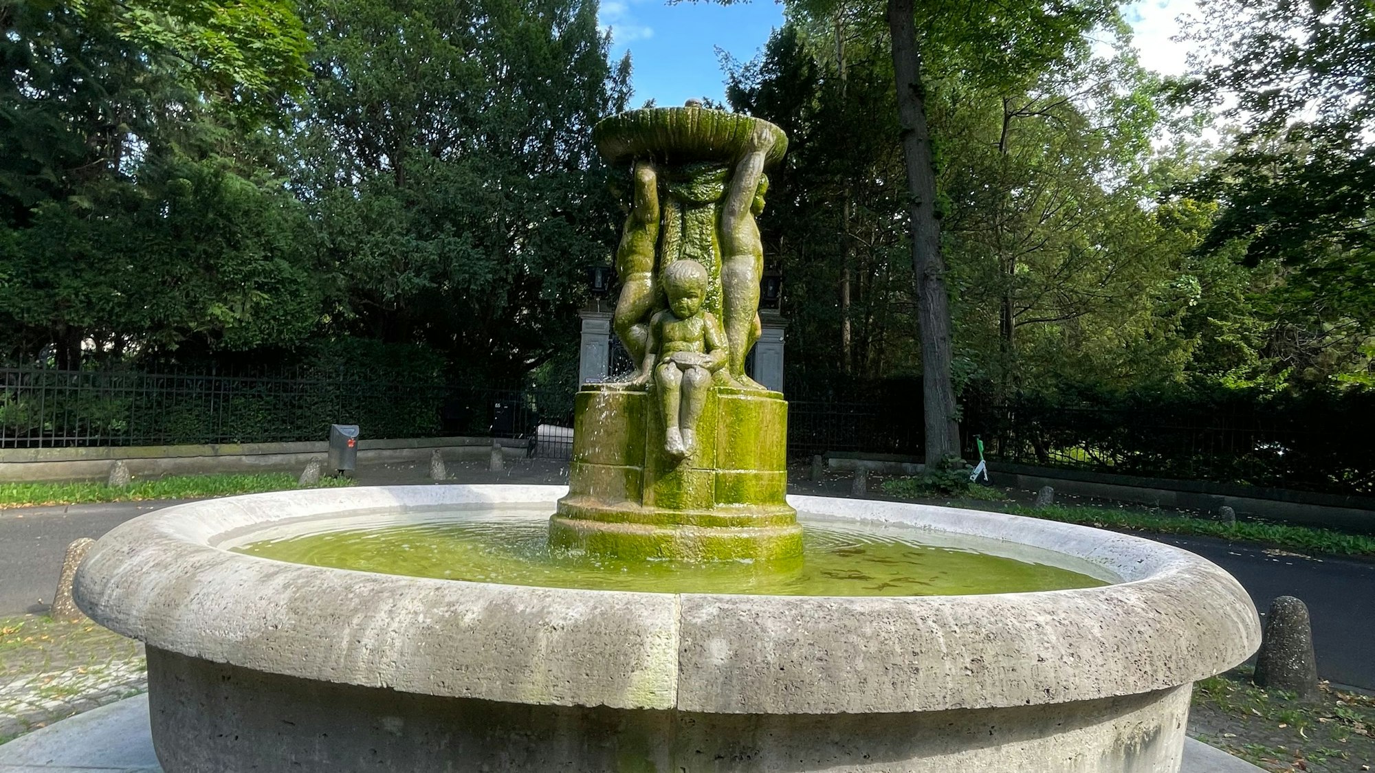 Ein Brunnen steht in einer Parkanlage.