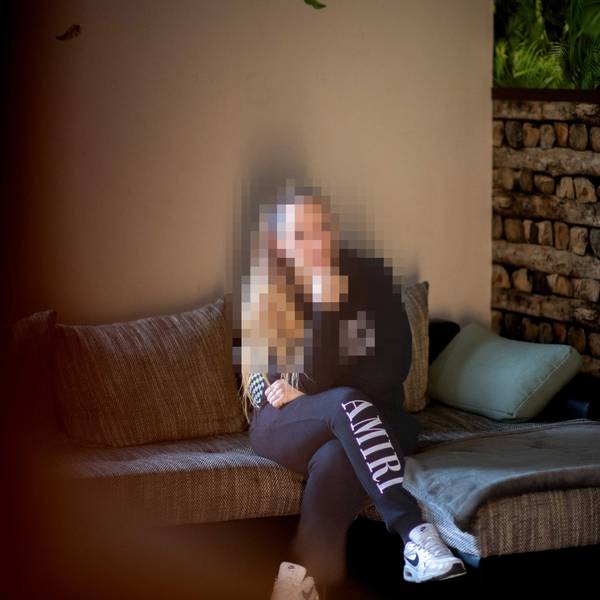 Das Bild zeigt Nadine Schäfer, wie sie auf einem Sofa sitzt. Ihr Gesicht ist zu ihrem Schutz gepixelt.