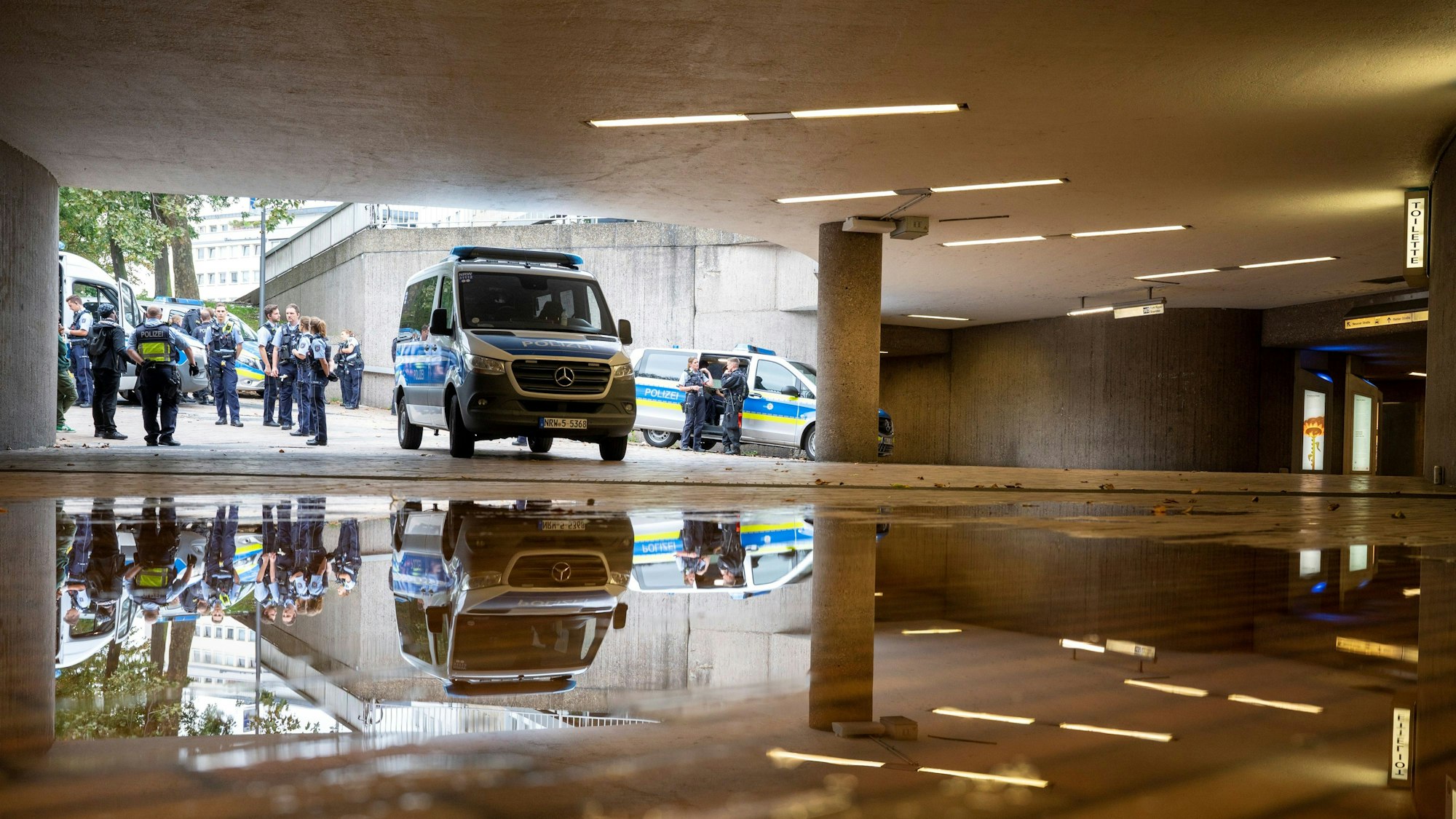 Polizisten und Streifenwagen stehen auf dem Ebertplatz vor dem Zugang zur Zwischenebene der KVB.