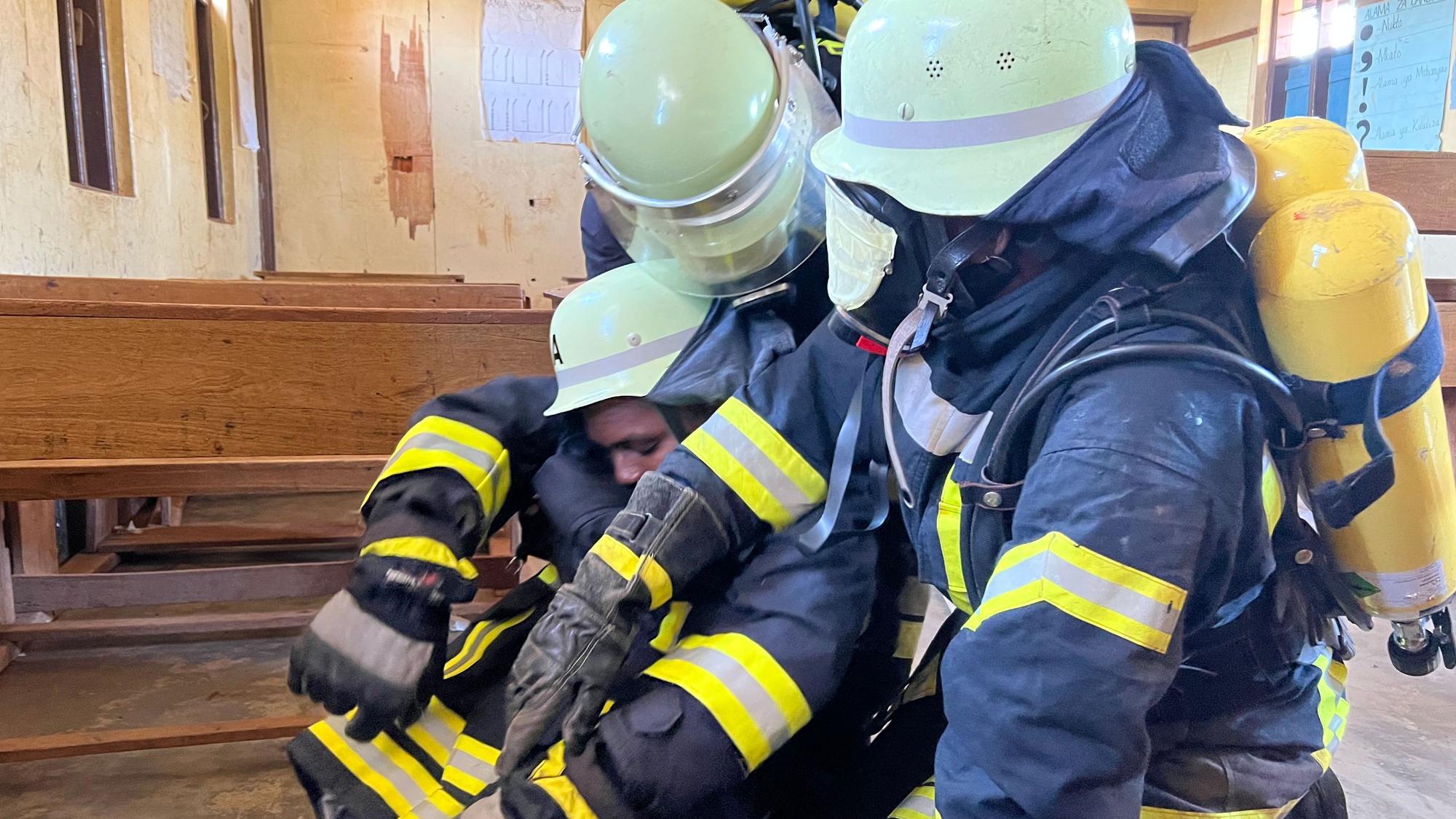 Ein Atemschutztrupp der Feuerwehr rettet einen dritten Feuerwehrmann.