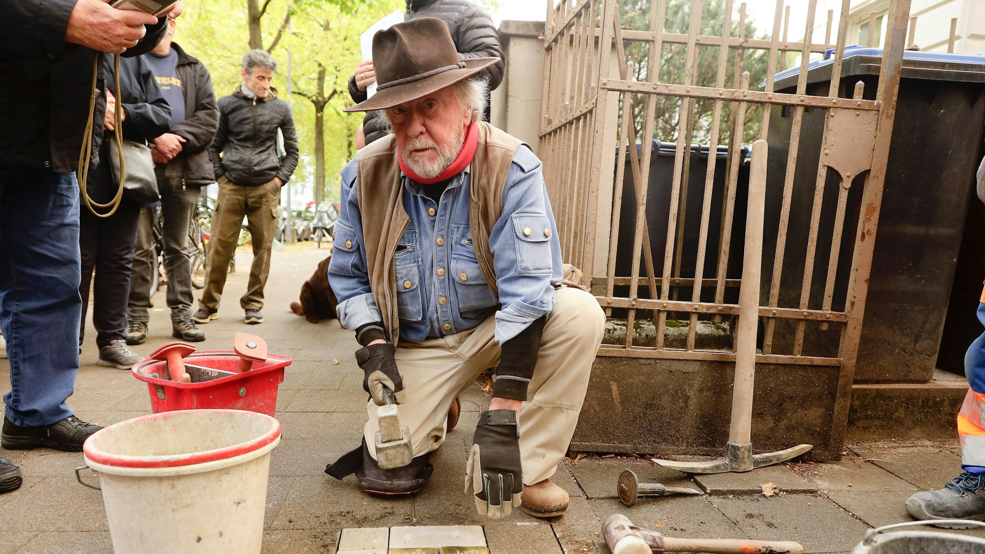 Älterer Mann mit Hut vor einer Reihe Stolpersteine