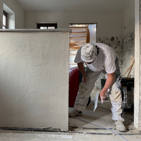 Ein Handwerker bearbeitet eine Wand mit einer Kelle.