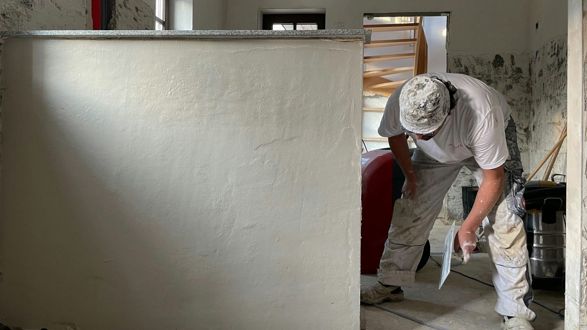 Ein Handwerker bearbeitet eine Wand mit einer Kelle.