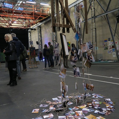 In einer großen Halle flanieren Besucher zwischen Kunstwerken.