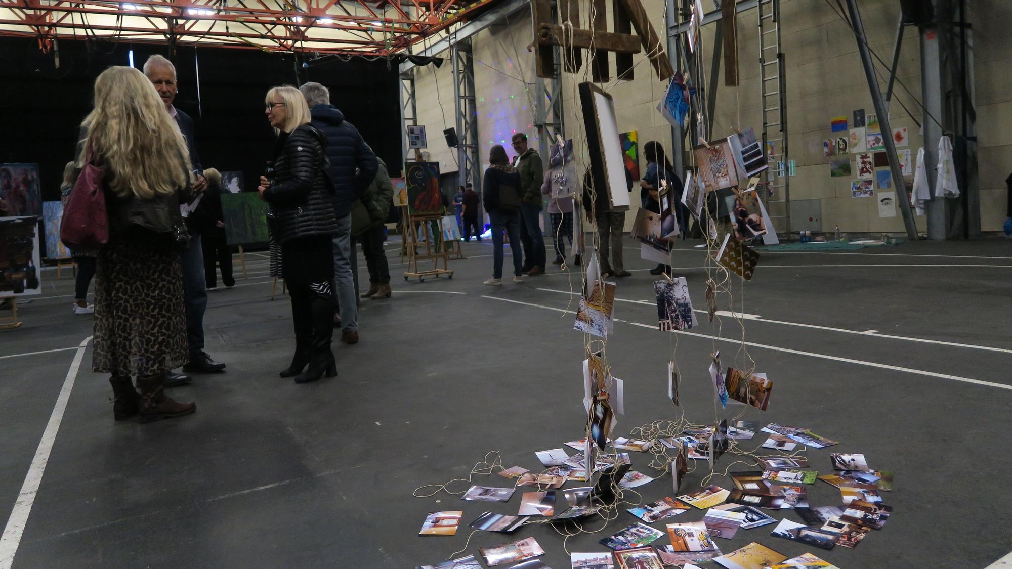 In einer großen Halle flanieren Besucher zwischen Kunstwerken.