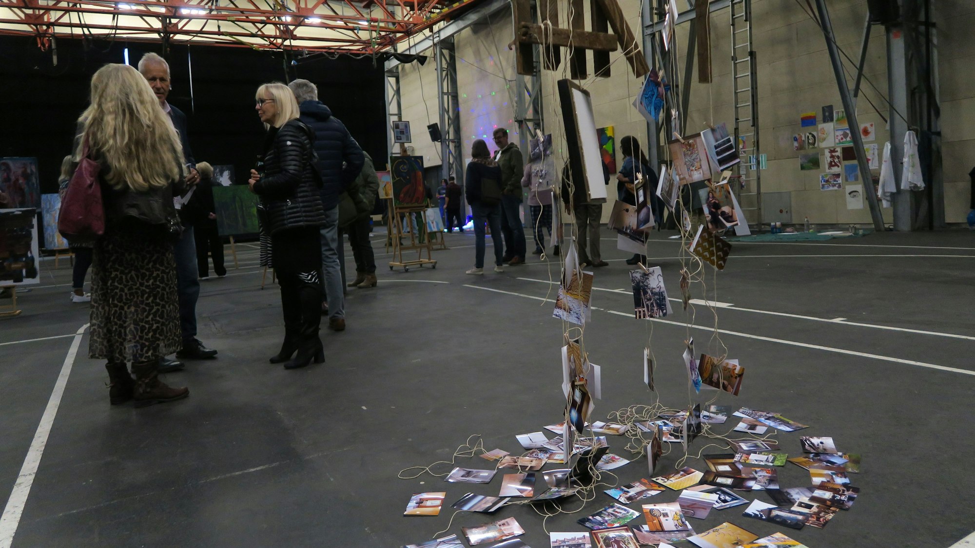 In einer großen Halle flanieren Besucher zwischen Kunstwerken.