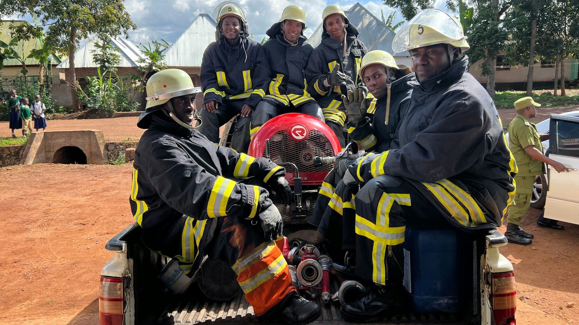 Foto von sechs Feuerwehrmännern mit Gerätschaften auf der Ladefläche eines Pick-ups.