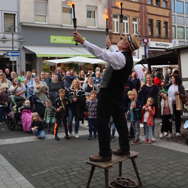 Zu sehen ist ein Gaukler, der vor großem Publikum mit Fackeln jongliert.