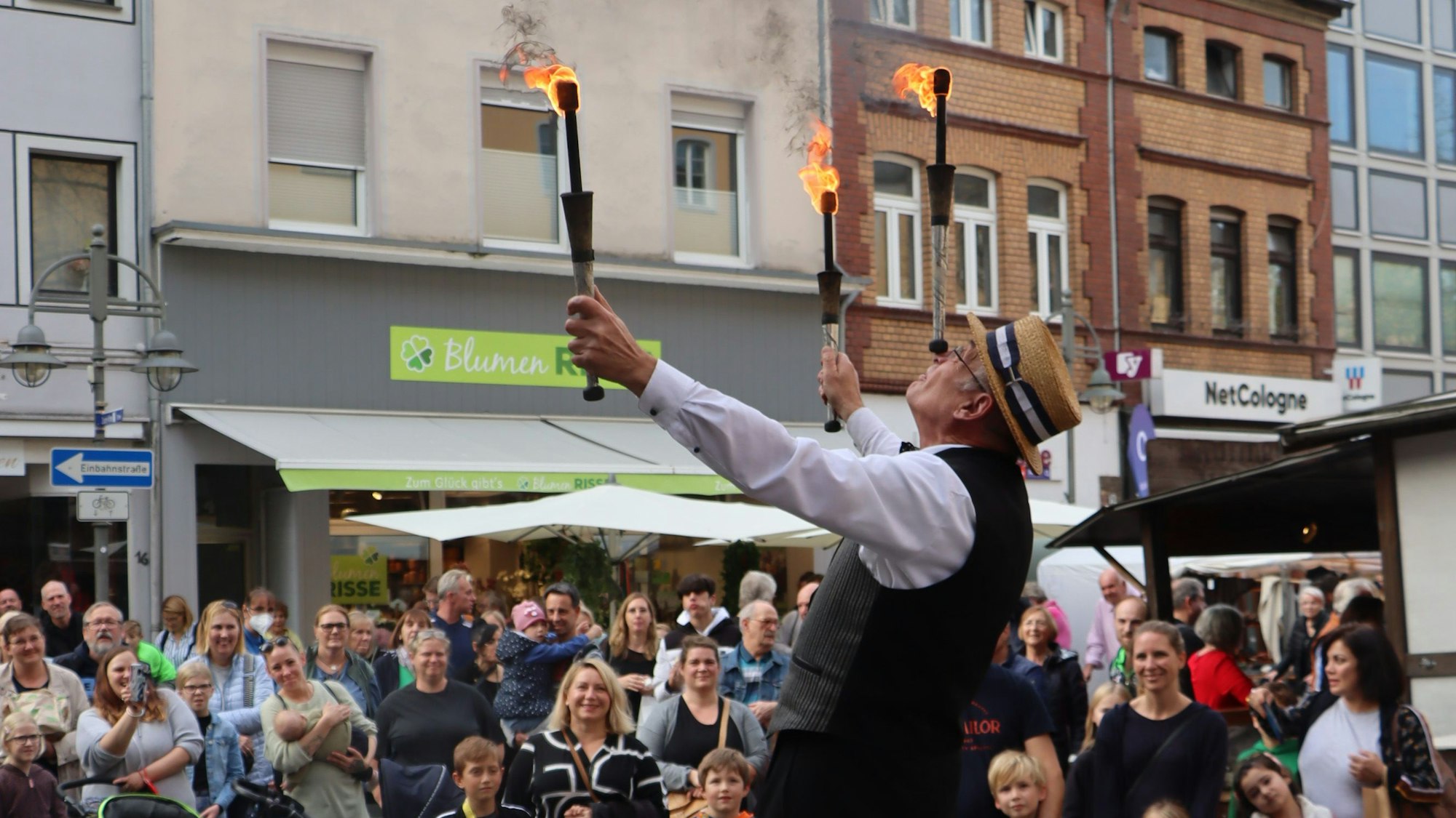 Zu sehen ist ein Gaukler, der vor großem Publikum mit Fackeln jongliert.