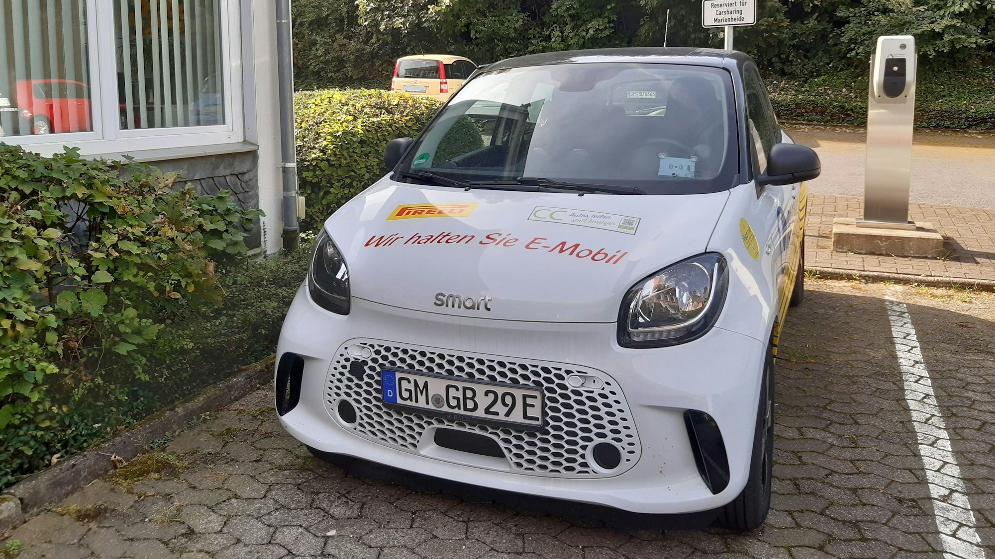 Ein E-Smart steht auf einem Parkplatz an einer Ladesäule.