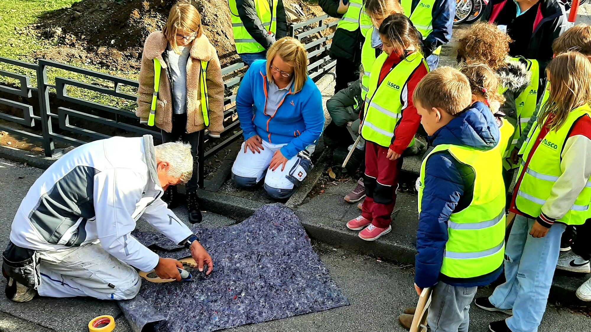 Rund um die GGS Im Kirchfeld in Lützenkirchen sprühten die Schülerinnen und Schüler des Schülerparlaments gemeinsam mit Malermeister Jens Wagner und Malermeisterin Maike Schmale Fußbadrücke auf die Wege, die einen sicheren Schulweg anzeigen und garantieren sollen.