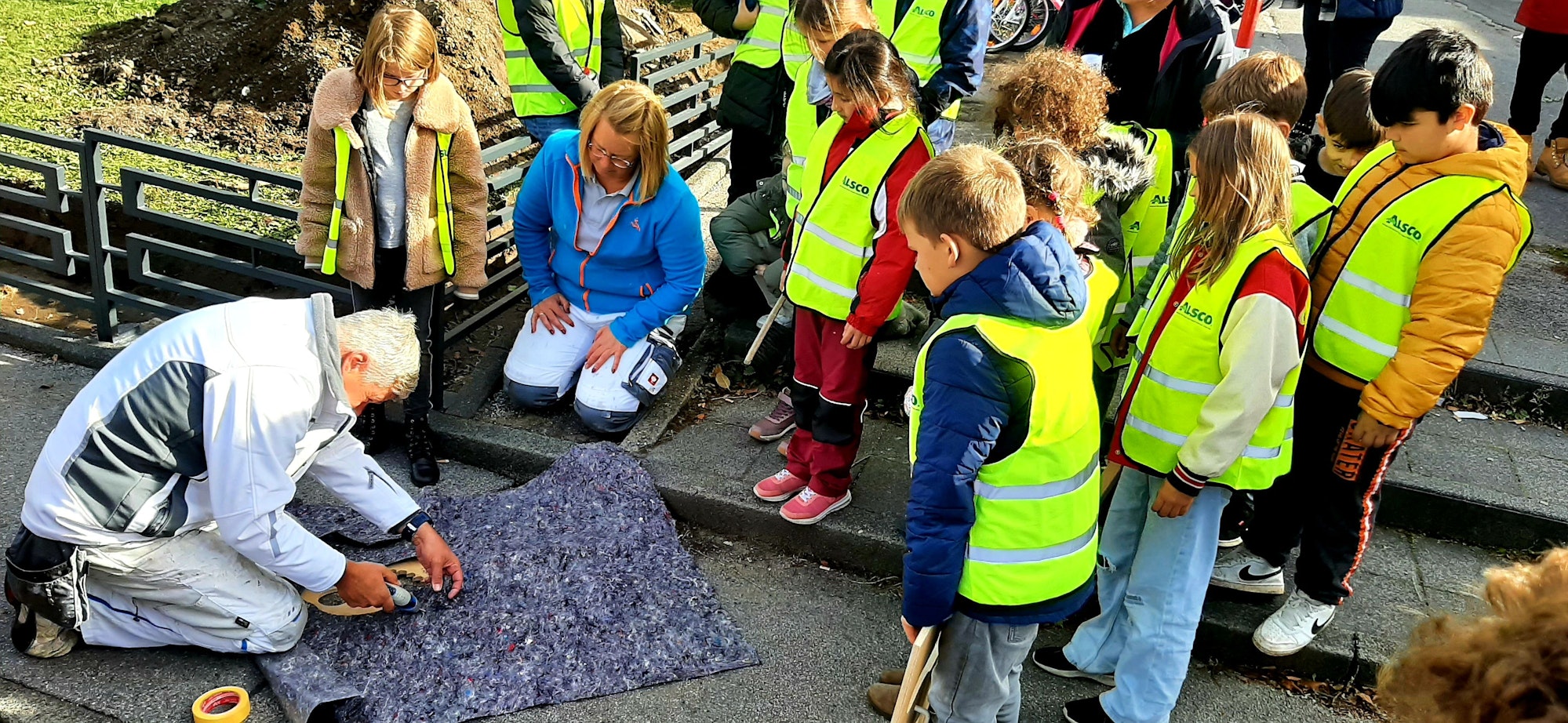 Rund um die GGS Im Kirchfeld in Lützenkirchen sprühten die Schülerinnen und Schüler des Schülerparlaments gemeinsam mit Malermeister Jens Wagner und Malermeisterin Maike Schmale Fußbadrücke auf die Wege, die einen sicheren Schulweg anzeigen und garantieren sollen.